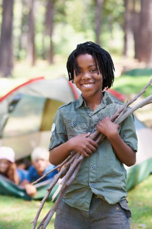 Téléchargez les photos : Bois, camping ou portrait de garçon africain dans la nature jouer, aventure ou vacances dans le parc. Détendez-vous, ramassez ou heureux enfant avec sourire ou bâtons dans les bois, le jardin ou la forêt pour la randonnée ou le bien-être. - en image libre de droit
