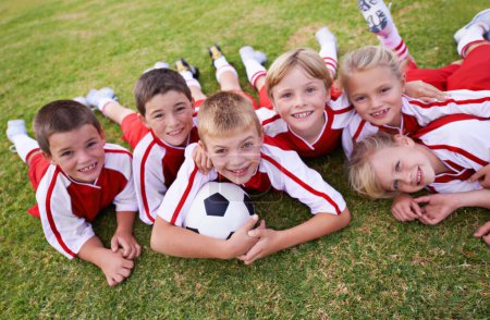 Niños, equipo de fútbol y retrato con pelota, niños y niñas en el campo, felices y unidos. Energía, deportes y amistad, juntos y felicidad para ganar, trabajo en equipo para el juego y la actividad física.