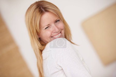 Photo for Happy woman, smiling and playful with wink, face and portrait in home, natural beauty and alone. Female, beautiful and thinking with idea, mature person and cheerful lady in house or blonde hair. - Royalty Free Image