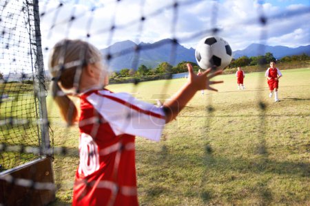 Photo for Girl, soccer and ball with goal keeper for save, match or game from scoring point on outdoor field. Team of football players playing together for sports, competition or training practice in nature. - Royalty Free Image