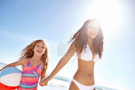 Photo for Happy mother, child and beach ball in sun for fun summer holiday, bonding or playing in nature. Mom holding hands with daughter or playful kid smile on weekend vacation by the ocean coast in sunshine. - Royalty Free Image