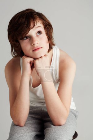 Photo for Thinking, fashion and boy child in a studio with dreaming, reflection or memory face expression. Youth, style and young kid model with casual, stylish and trendy outfit isolated by gray background - Royalty Free Image