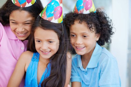Foto de Feliz, fiesta de cumpleaños y niños con sombreros en su casa para la celebración y la unión. Sonríe, niños jóvenes emocionados y dulces en el evento con la amistad, la juventud y la infancia en la casa moderna - Imagen libre de derechos