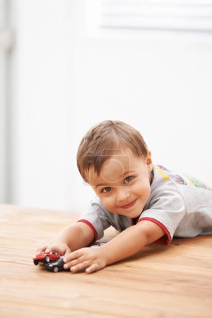 Photo for Cars, toys and portrait of child by table playing for learning, development and fun at modern home. Cute, sweet and boy kid enjoying a game with plastic vehicles by wood for childhood hobby at house - Royalty Free Image