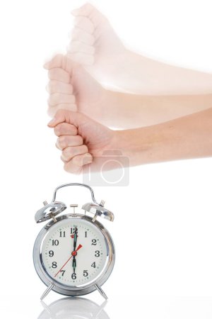 Photo for Person, hand and hitting alarm clock for alert, wakeup or deadline on a white studio background. Closeup of fist slamming down on time for stop in motion blur, schedule or management for planning. - Royalty Free Image