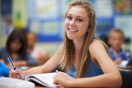 Photo for Girl, classroom and writing in portrait for education, learning and notes for knowledge in high school. Female person, book and pride for assessment or test, studying lesson and happy at academy. - Royalty Free Image