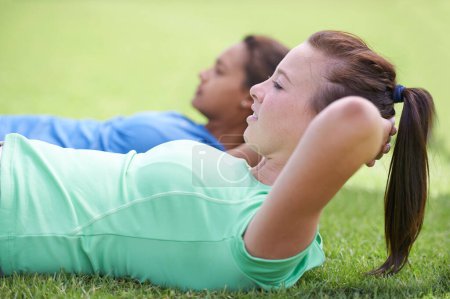 Photo for Woman, sit ups and workout on green grass for fitness or outdoor exercise together in nature. Young active female person or people in core, abs or strength training while lying on field outside. - Royalty Free Image