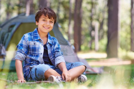 Téléchargez les photos : Camping forestier ou portrait d'enfant heureux dans la nature pour jouer, aventure ou vacances dans le parc. Détendez-vous, confiant ou enfant mâle avec le sourire dans les bois, le jardin ou l'herbe pour une randonnée amusante ou bien-être. - en image libre de droit
