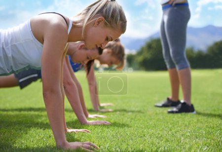 Photo for Women, teamwork and push ups on grass for fitness with exercise, training and coach on sports field. Athlete, people and collaboration on ground with physical activity for healthy body and wellness. - Royalty Free Image