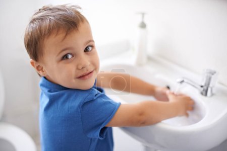 Photo for Child, boy and washing hands in portrait, water and prevention of germs or bacteria in bathroom. Male person, kid and learning at basin or cleaning and sanitary, liquid and disinfection at home. - Royalty Free Image