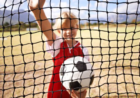 Photo for Little girl, soccer player and ball on goal net, smile and happy for game, field and child. Outdoor, playful or sport for childhood, portrait and athlete for match, alone or outside on football pitch. - Royalty Free Image