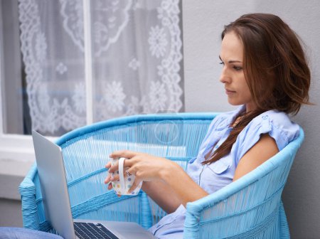 Photo for Woman, reading and laptop for outdoor by house, porch and relax wellness with coffee break for freelancer. Person, email and computer in chair for morning espresso, remote work and job in technology. - Royalty Free Image
