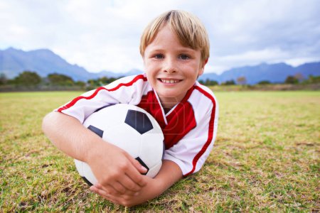 Photo for Kid, soccer player and ball with portrait, happy and ready for game, field and child. Outdoor, playful and sport for childhood, blue skies and athlete for match, alone and outside on football pitch. - Royalty Free Image