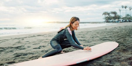 Photo for Surfing, ocean and woman with wax for surfboard for water sports, fitness and freedom on beach. Nature, travel and happy Japanese person on sand for wellness on holiday, vacation and adventure by sea. - Royalty Free Image