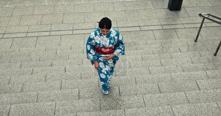Téléchargez les photos : Femme japonaise, religion et promenade en kimono sur les escaliers, la ville et la culture par patrimoine en plein air. Jeune, détendez-vous ou vêtements traditionnels en tokyo avec Voyage, étapes ou fierté de la mode autochtone. - en image libre de droit