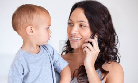 Photo for Mom holding toddler in home with phone call, smile and child care with support in morning. Happy woman, baby boy and bonding together in bedroom with chat on cellphone, multitasking and mothers love - Royalty Free Image