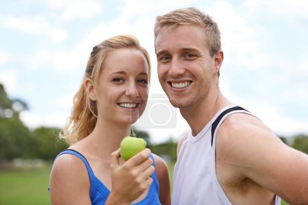 Photo for Couple, sport and portrait with apple, fitness and exercise on a field with a smile and wellness. Happy, healthy and athlete outdoor with fruit, nutrition and health together for workout and training. - Royalty Free Image