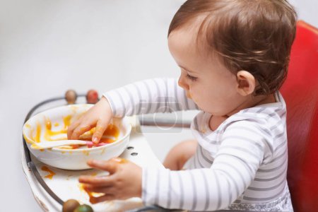 Photo for Eating, puree and girl baby in chair with vegetable food for child development at home. Cute, nutrition and hungry young kid or toddler enjoying healthy lunch, dinner or supper meal at house - Royalty Free Image