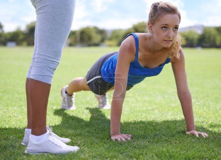 Téléchargez les photos : Femmes, entraîneur et push-ups sur l'herbe pour la forme physique avec l'exercice, l'entraînement et l'entraînement sur le terrain de sport. Athlète, personne et confiance sur le terrain et activité physique pour un corps, un bien-être et un cœur sains. - en image libre de droit
