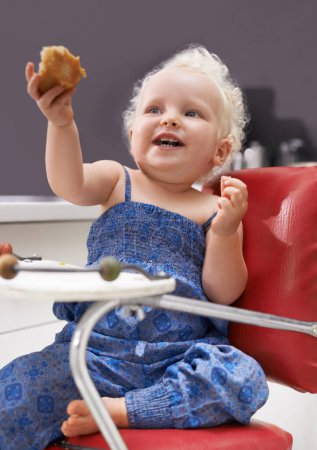 Photo for Child, high chair and eating muffin, food and breakfast sweets at home in kitchen. Young kid, hungry toddler and cupcake dessert, sugar and pastry snack for happy cute girl in house in the morning. - Royalty Free Image