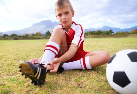 Photo for Boy, soccer player and ball with shoe laces, portrait and ready for game, shoes or child. Outdoor, exercise and sport for childhood, person and athlete for match, training and workout on pitch. - Royalty Free Image