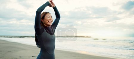Téléchargez les photos : Surfeur, Japonais et femme s'étirant à la plage, heureux pour la forme physique et les sports extrêmes avec vue sur l'océan, les vagues et les voyages. Flexibilité, échauffement et exercice en plein air, surf et nature avec sourire au Japon. - en image libre de droit