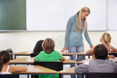 Photo for Teacher, kids and students in classroom for learning, education and math support or development at desk. Happy woman with children for teaching numbers, helping with knowledge and questions at school. - Royalty Free Image