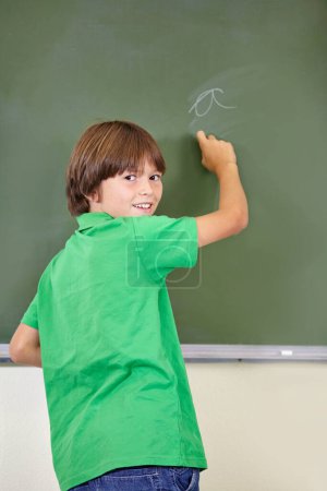 Photo for Portrait, smile and boy drawing on a chalkboard for child development, answers and art for learning. Academic, creative and kid student writing letters in the classroom with art, excited and happy. - Royalty Free Image