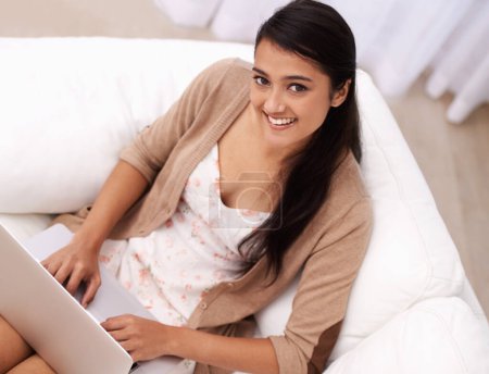 Photo for Portrait of woman on couch with laptop, smile and relax with remote work, website and browse in living room. Happy girl on sofa with computer for freelance job, online research and internet in home - Royalty Free Image
