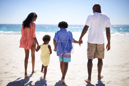Téléchargez les photos : Se tenir la main, marcher et la famille noire à la plage ensemble en vacances tropicales, aventure ou vacances. Amour, Voyage et jeunes parents africains avec des filles enfants par l'océan pour le week-end de liaison voyage - en image libre de droit
