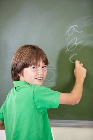 Photo for Portrait, knowledge and boy drawing on a chalkboard for child development, creativity and art for learning. Academic, face and kid student writing with information in the classroom and answers. - Royalty Free Image