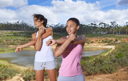 Téléchargez les photos : Jeunes femmes, étirement et remise en forme à la campagne pour l'exercice en plein air par les arbres et le ciel bleu. Diversité, les adolescents et l'entraînement cardio dans les vêtements de gymnastique, en bonne santé et bien-être avec la formation en forêt. - en image libre de droit