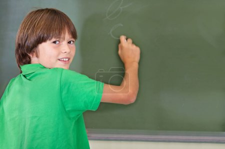 Photo for Writing, chalkboard and portrait of kid at school with education and answer for learning. Drawing, knowledge and youth development in study lesson with boy in classroom with chalk and solution. - Royalty Free Image