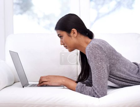 Photo for Woman, laptop and relax on sofa for online education, e learning or research for home school or streaming website. Young person or student typing on a computer or notebook in living room or lounge. - Royalty Free Image