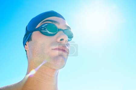 Photo for Swimmer, sky and face of sports man determined for exercise, outdoor workout or training routine. Swimwear, sunshine or athlete with cap, goggles and commitment to summer challenge, fitness or cardio. - Royalty Free Image