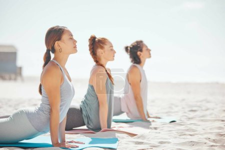 Téléchargez les photos : Yoga d'équipe sur la plage, méditation relaxante dans la nature et zen pendant les cours de pilates à la mer, entraînement en collaboration pour le bien-être en mer et entraînement spirituel en été. Femmes faisant du sport océan exercice. - en image libre de droit