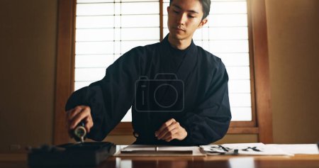 Photo for Paper, ink and traditional Asian man for writing letters, notes and text for documents or script. Creative writer, culture and person with paint, tools and desk for art, calligraphy and handwriting. - Royalty Free Image