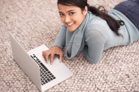 Téléchargez les photos : Portrait de femme heureuse sur tapis avec ordinateur portable, détendez-vous et naviguez avec étude, recherche et web dans le salon. Étudiante à l'université fille sur le sol avec ordinateur, elearning et éducation en ligne à la maison - en image libre de droit