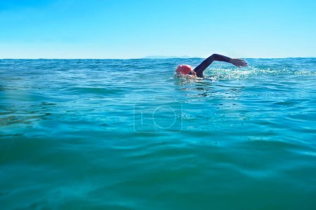 Photo for Swimming, stroke and person in ocean water in summer for exercise, training or workout on mockup space. Sea, sport and a young athlete outdoor for fitness, health and triathlon competition in nature. - Royalty Free Image