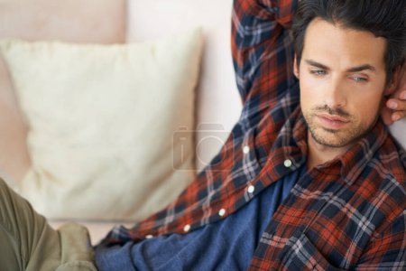 Photo for Relax, thinking and man on sofa in home for afternoon nap, resting and calm in living room. Tired, thoughtful and person on couch lying for dreaming, comfortable and peace in apartment for wellness. - Royalty Free Image