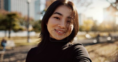 Téléchargez les photos : Femme japonaise, heureuse et portrait dans le parc, la nature et le chemin avec soleil, ville et bâtiments avec fierté. Fille, personne et sourire par la pelouse, l'herbe et les arbres dans le métro urbain, en plein air et Voyage à Tokyo. - en image libre de droit