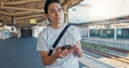 Photo for Man, check phone and waiting at train station with reading, thinking and location with digital schedule. Man, travel and smartphone for transportation app, time management or map for tourism in Japan. - Royalty Free Image