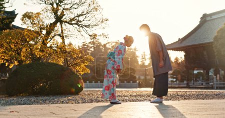 Photo for Japanese people at temple, bow and traditional clothes with hello, nature and sunshine with respect and culture. Couple outdoor, greeting with modesty and tradition, polite and kind for religion. - Royalty Free Image