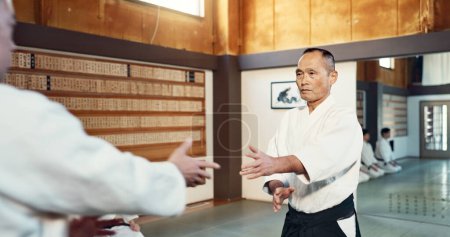 Téléchargez les photos : Sensei japonais, aikido et instructeur pour le combat, les arts martiaux modernes et la classe en légitime défense. Enseignant, respect et courbure en tant que formateur dans l'énergie de la vie, homme et fort dans l'entraînement dans la place du dojo. - en image libre de droit