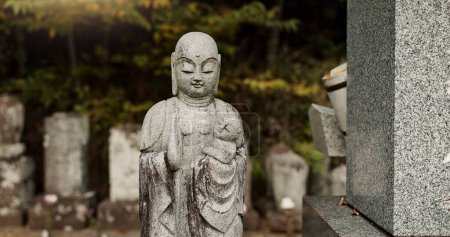 Foto de Buddha, estatua en el cementerio de Japón con el niño para la seguridad, la protección y la escultura al aire libre en la naturaleza. Jizo, lápida y lápida conmemorativa con historia, cultura y monumento para hacer turismo o viaje. - Imagen libre de derechos