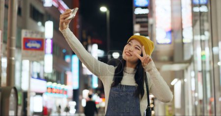 Photo for Peace, hands and selfie by Japanese woman in a city for travel, adventure or journey outdoor. V sign, emoji or happy lady influencer in Japan for content creation, blog or social media live streaming. - Royalty Free Image