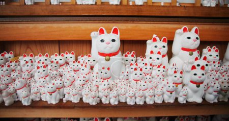 Photo for Japanese, traditional and neko maneki or good luck cat in shop for fortune, culture or heritage. Sculpture figure, gotokuji statue and travel destination in Tokyo for local history, spiritual or gift. - Royalty Free Image
