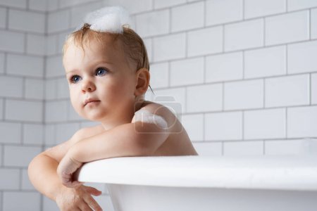 Photo for Boy, baby and child in bath of bubbles, tub and cleaning with water for skincare, morning routine and wellness at home. Toddler kid, thinking and washing hair with soap, foam and hygiene in bathroom. - Royalty Free Image