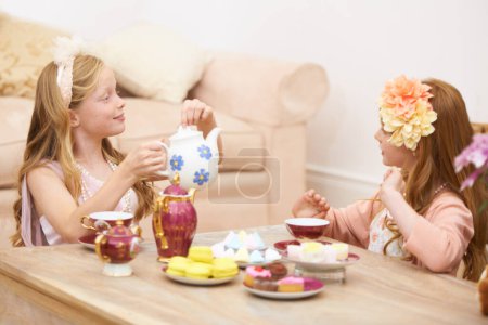 Photo for Girls, friends and playing tea party in home for fancy dress up fantasy for game, bonding or birthday. Female people, siblings and flower crown or pot for drinking or eat macarons, snack or chatting. - Royalty Free Image