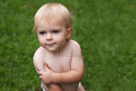Photo for Baby, standing and nature on grass, development and growth for curiosity, backyard and home. Toddler, child and face in garden, alone and childhood memories for wellness, outdoor and exploring. - Royalty Free Image